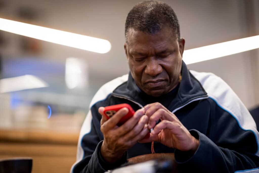 A photo of a man using a smart phone with a red case.